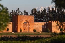 Image du Maroc Professionnelle de  Hormis les remparts de Marrakech qui sont construits entièrement en pisé selon une technique séculaire par l'Almoravide Ali Ben Youssef au début de XIIème siècle pour se protéger des attaques extérieures. La ville rouge dispose d’autres murailles qui protègent les parcs comme celle-ci qui clôturent les jardins de l'Agdal Ba Ahmed. Au fond la chaine de montagne du Haut Atlas enneigé surplombe la plaine du Haouz où de nombreux palmiers des jardins apportent à ce paysage un contraste très accentué, 3 Décembre 2012. (Photo / Abdeljalil Bounhar) 